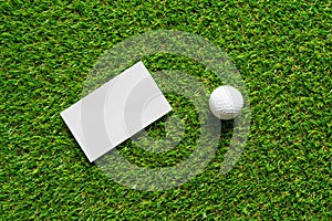 White paper background and golf ball on green grass of golf course.