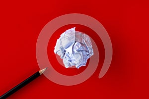 White paper ball with a black pencil on a red background.
