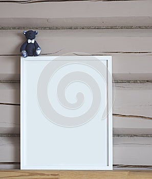 White paper blank interior poster, with blue bear toy, isolated vertical mock up with frame on beige wooden wall background, child