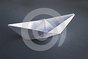 White paper boat origami isolated on a grey background