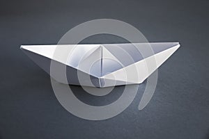 White paper boat origami isolated on a grey background