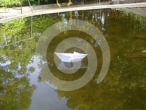 White paper boat at stale water in garden