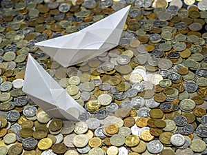White paper boats in sea made from coins: sailing and sinking.