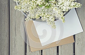 White paper card with closeup lilac flowers and wooden background