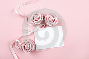 White paper card decorated with pink bow and rose scented candle