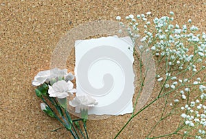 White paper card with flower on wooden corkboard