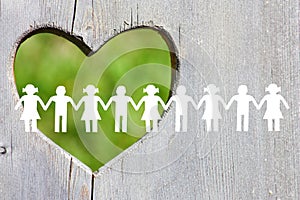 White paper children silhouette on wooden background with green heart