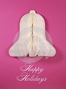 White paper Christmas bell ornament against a pink background