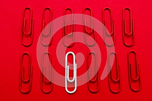 White paper clip unique concept idea on red background, stand out from the crowd