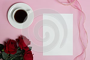 White paper with coffee cup with red roses over the pink background.
