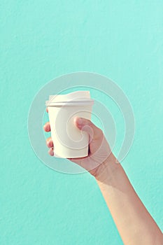 White paper cup of coffee in hand