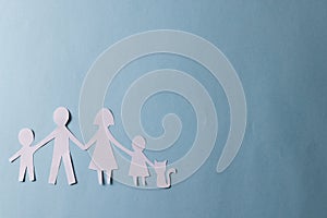 White paper cut out of family with two children and cat and copy space on blue background