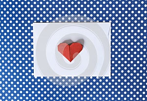 White paper envelope and origami heart on a blue background polk