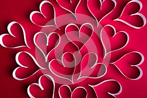 White paper hearts on the red paper background. Colorful Valentine background concept