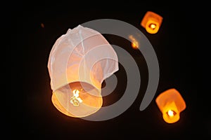 White paper lanterns of desires with a burning candle inside flying up into the night sky