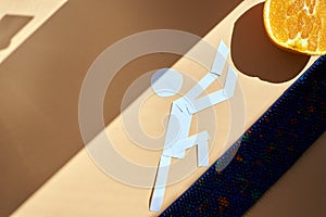 A white paper man pushes an orange uphill on a barbed massager. top view. healthy lifestyle. Subject and promotional photography.