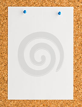 White paper note sheet with blue push pin on cork board