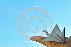 White paper origami bird on blue sky background