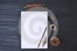 White paper and pencil with decoration on the wooden desk, top view.