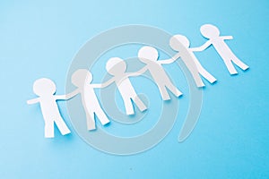 White paper people holding hands. Blue background