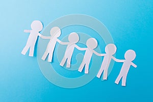 White paper people holding hands. Blue background