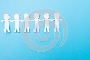White paper people holding hands. Blue background. Place for text
