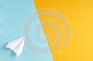 White paper plane on blue and yellow background composition