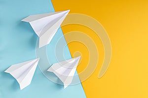 White paper planes on blue and yellow background composition