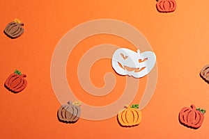 White paper pumpkin on orange background with copy space