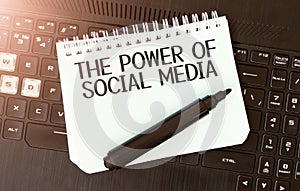 White paper sheet with text THE POWER OF SOCIAL MEDIA on the black laptop