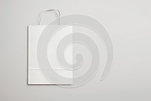 White paper shopping bag with handles on light background. 3d re