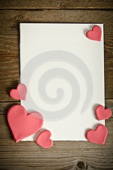 White paper with small pink hearts on a wooden background