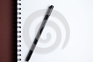 White paper spiral notebook and black pen