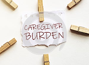 White paper with text Caregiver burden with clothespins on white background