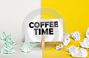 White paper with text coffee time on a clothespin on yellow and white backgrounds with paper wads of different colors