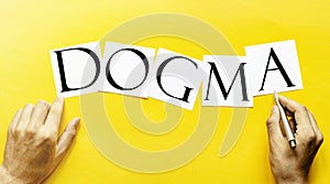 White paper with text DOGMA on a yellow background with man`s hands