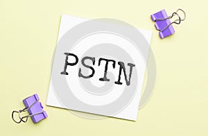 white paper with text pstn on a yellow backgroundd with stationery