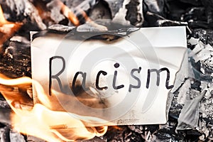 White paper with text of racism in fire. Concept of nationalism and ethnic equality. Social Issues. Discrimination, racial problem