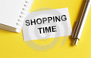 White paper with text Shopping Time on a yellow background with stationery