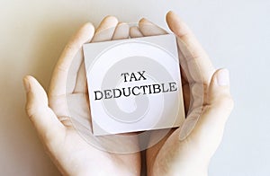 White paper with text TAX DEDUCTIBLE in male hands on a white background