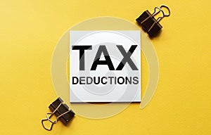 White paper with text Tax Deductions on a yellow background with stationery