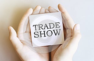 White paper with text Trade Show in male hands on a white background