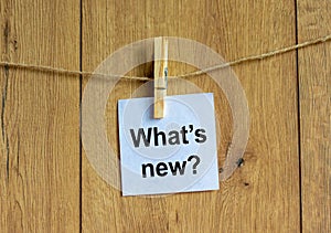 White paper with text `Whats New`, clip on wood clothespin. Beautiful wooden background. Business concept. Copy space photo