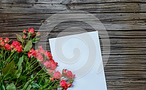 White paper on wooden surface with rose bundle