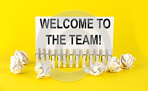 White paper on the yellow background with text WELCOME TO OUR TEAM