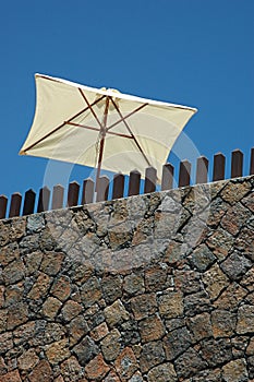 White parasol set against a blue sky, part of the outdoors furniture of a private property