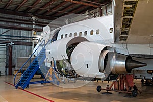 White passenger aircraft in the aviation hangar. Jetliner under maintenance