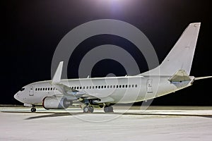 White passenger aircraft on the night airport apron at winter
