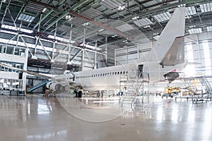 White passenger airliner in the aviation hangar. Airplane under maintenance