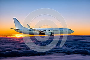 White passenger airliner flies in the sunset sky